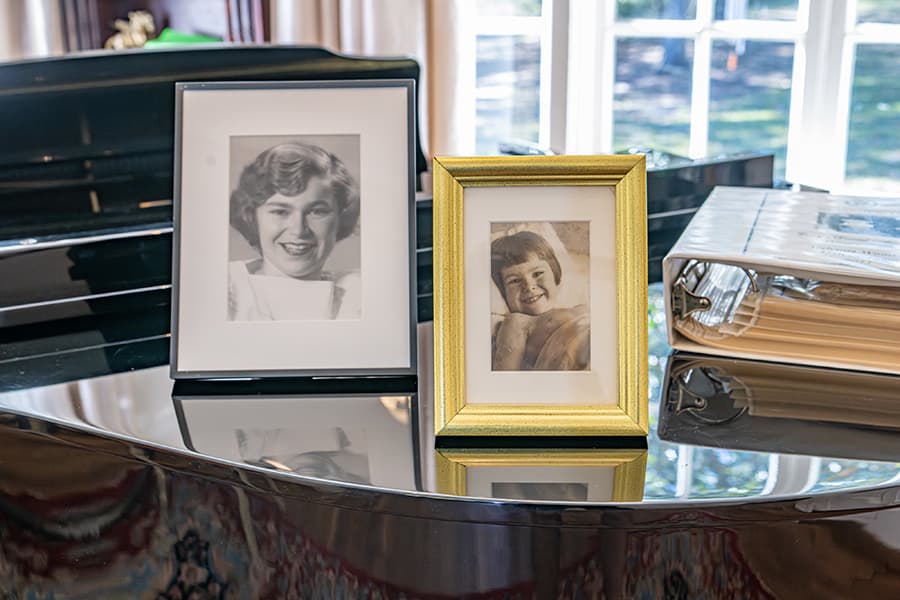 Two framed black-and-white photos of smiling children on a glossy piano surface.