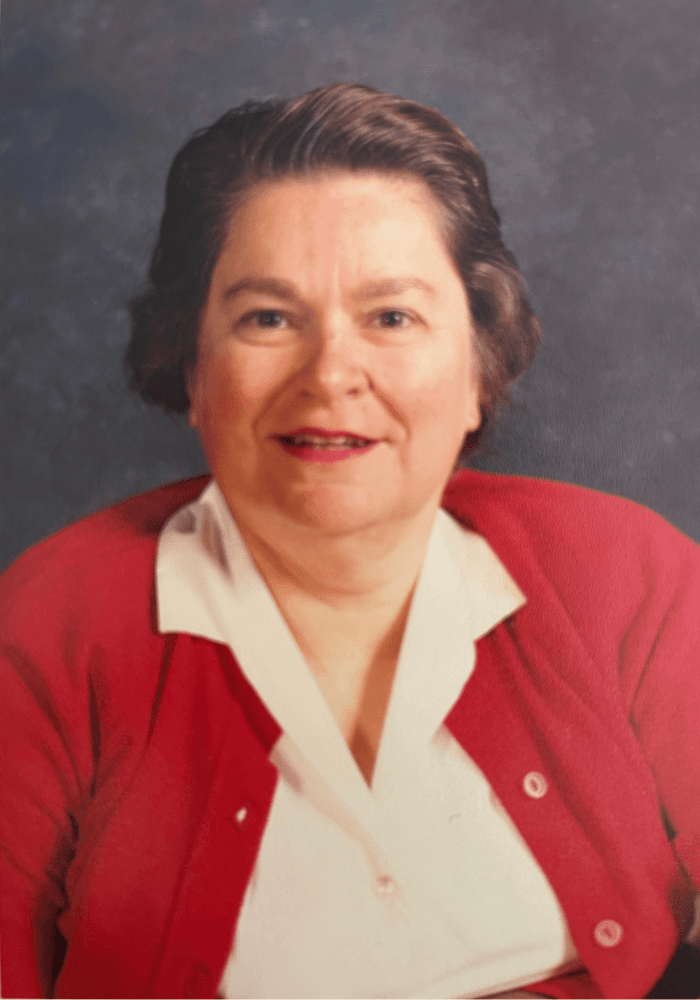 A woman in a red cardigan smiles warmly at the camera.
