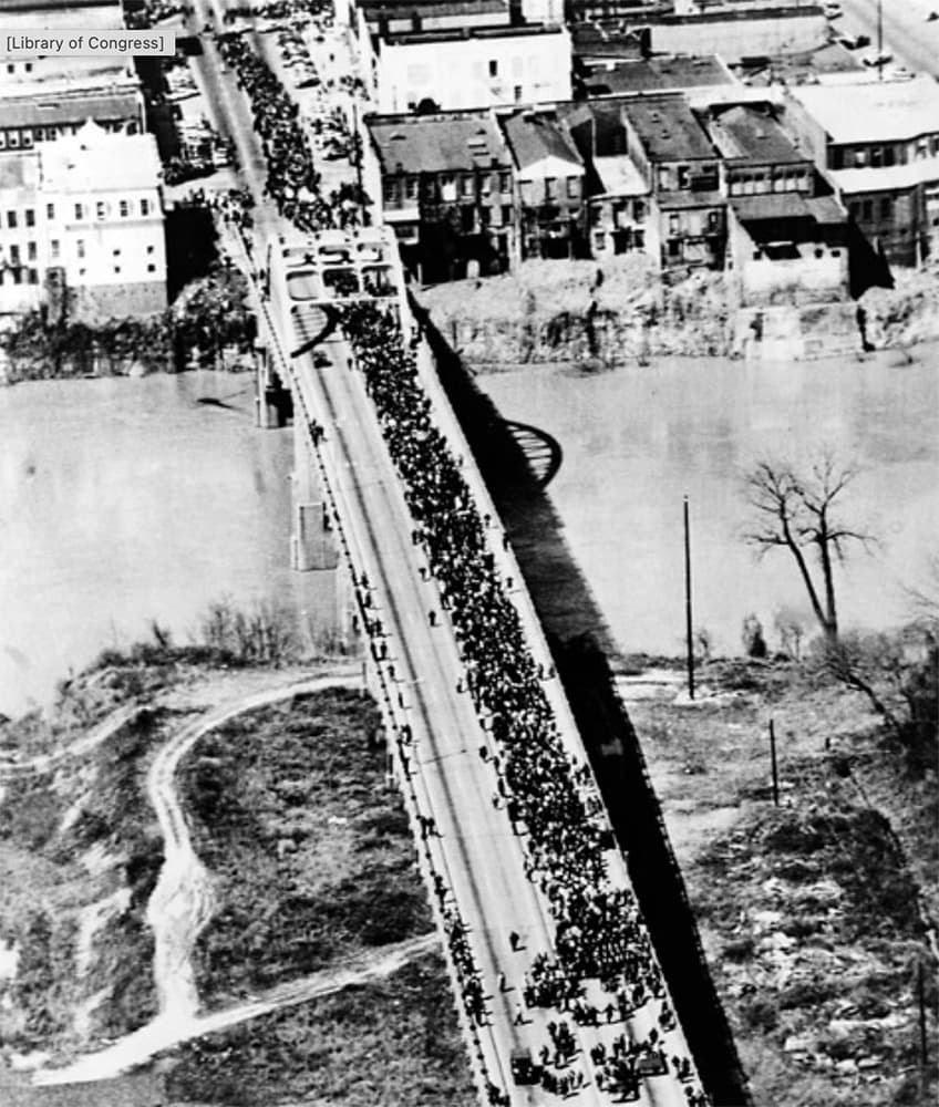 Aerial view of a large crowd marching across a bridge.