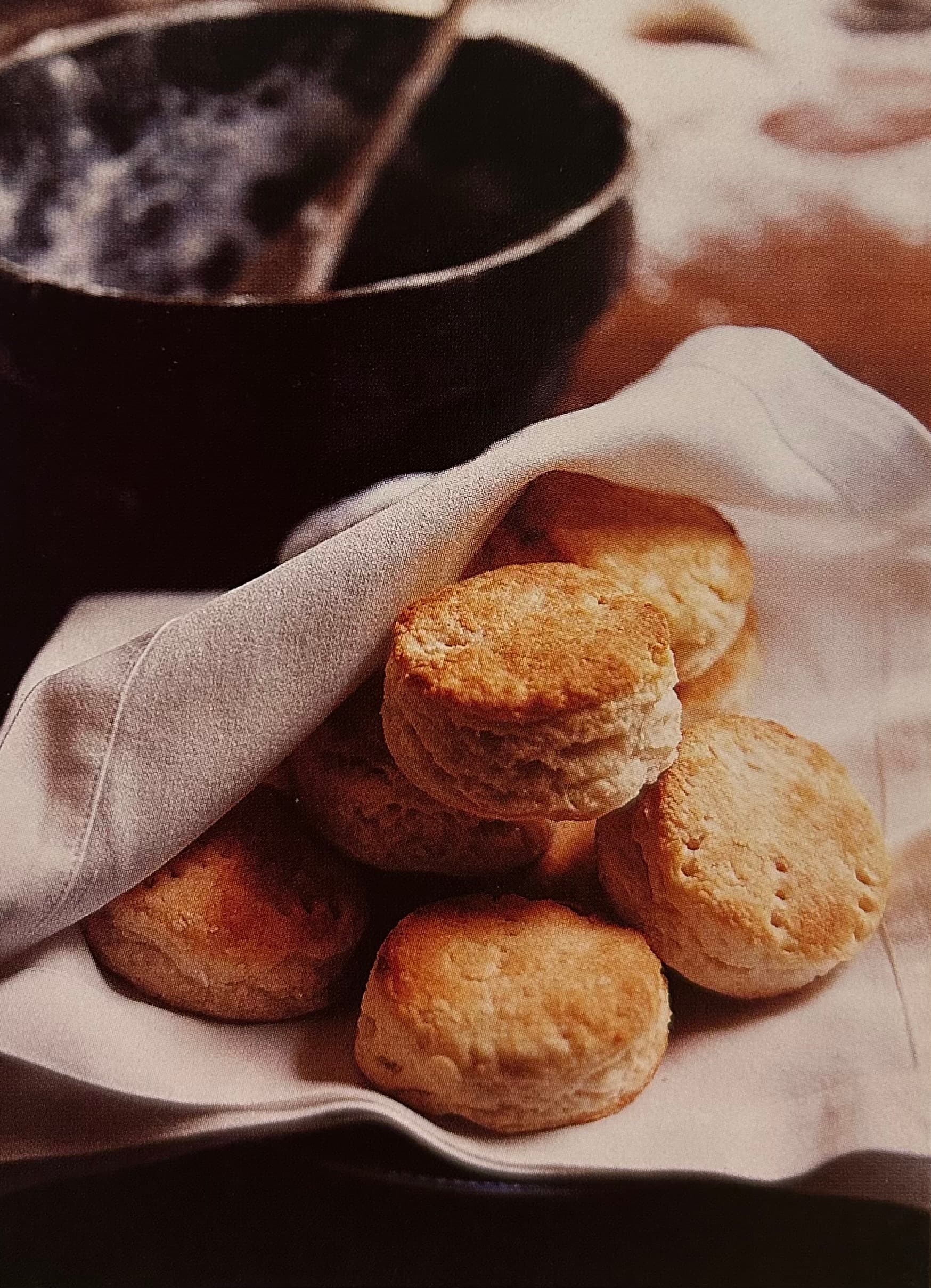 A basket of freshly baked biscuits wrapped in a cloth.